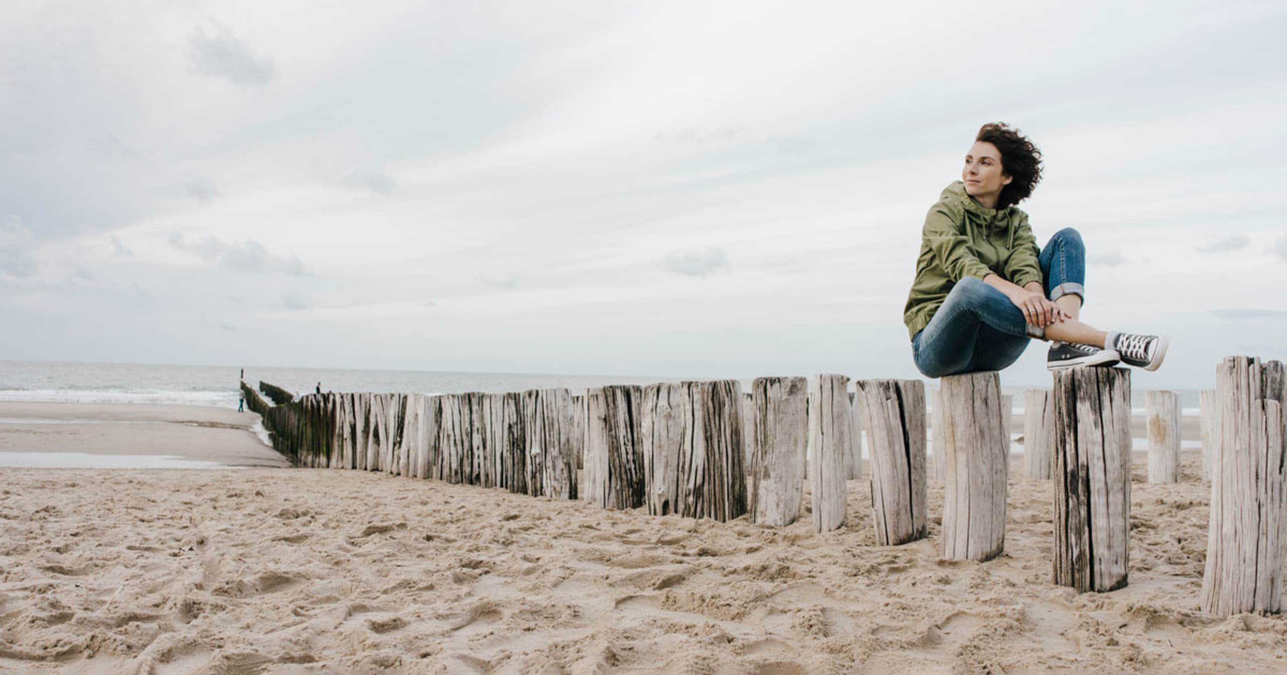 A woman sitting on logs on the beach.