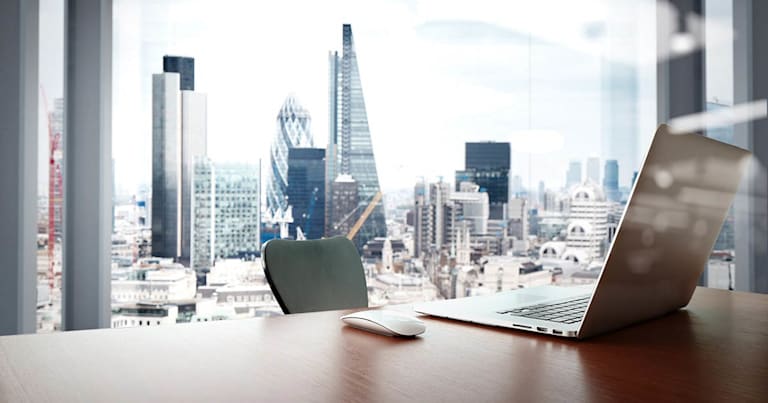 A desk and chair with a large window behind them looking out over a city skyline.