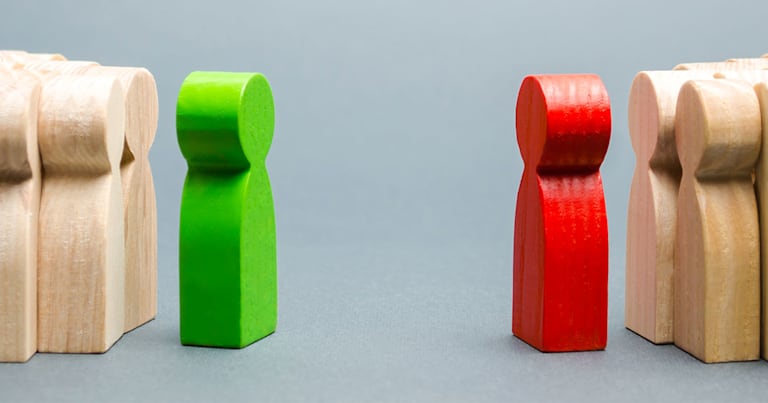 A green wooden toy faces a red wooden toy. Each color toy has a group of uncolored toys behind them.
