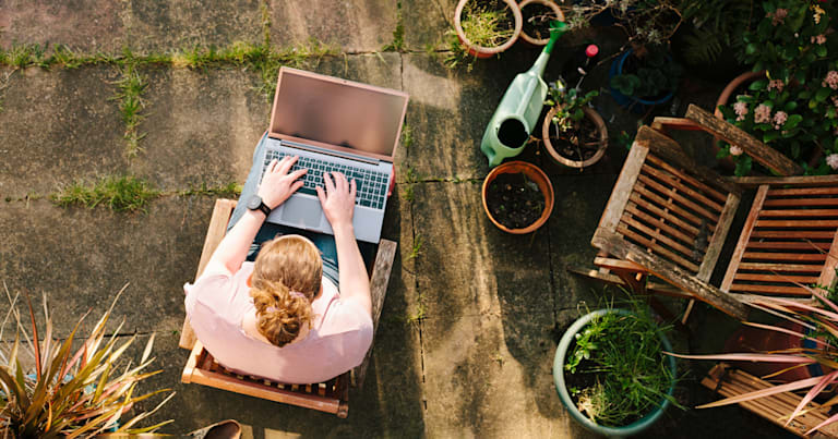 A woman working on her laptop outside.