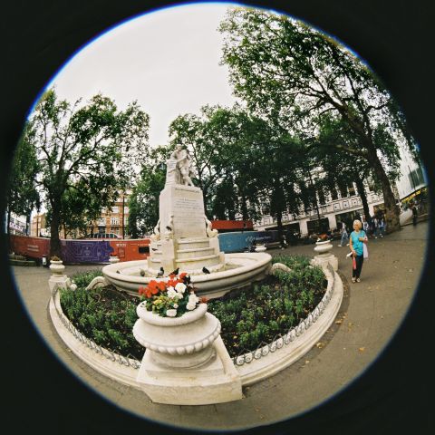 The statue of William Shakespeare is the centrepiece of Leicester Square Gardens, cloudy morning light.