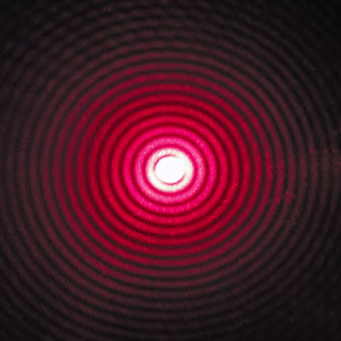 A diffraction pattern of a laser beam passing through a small circular aperture.