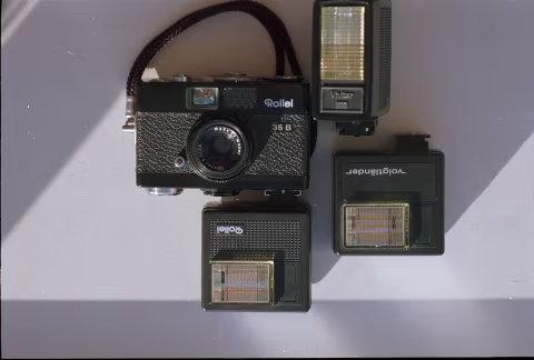 Rollei 35B with various flashes, attacheable to its bottom plate.