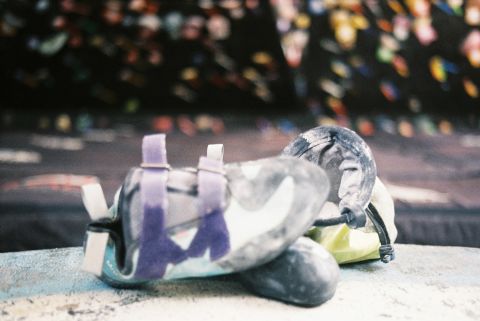 Climbing shoes and a chalk bag, bouldering essentials. The climbing wall is in the background. Shot with Canon QL25 on Fujicolor 200.