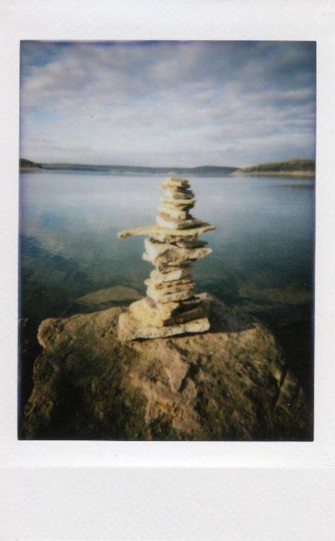 Photo of Lake Tenkiller in Oklahoma of some rocks stacked by the water. Taken with Lomo Instant Mini.