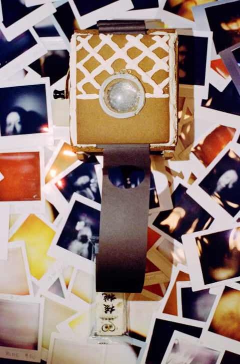 Gingerbread 2, with its long paper shutter and a large sugar lens, is laid on top of many wasted and successful Instax Square frames shot through edible optics.