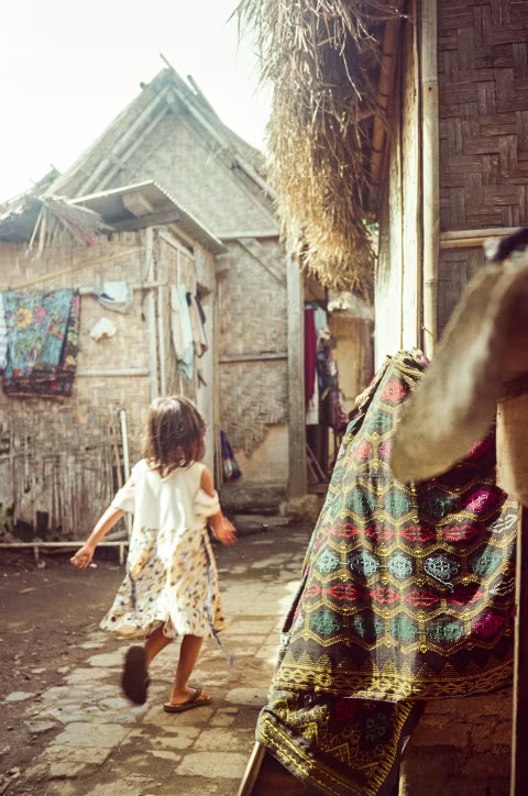 Straw houses, hand-woven cloth, and a happy child. Captured on Kodak ColorPlus 200.