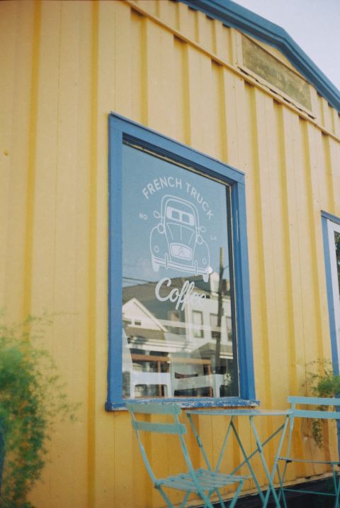 A cafe window with beautiful artwork, lettered “FRENCH TRUCK,” reflecting the houses across the street.