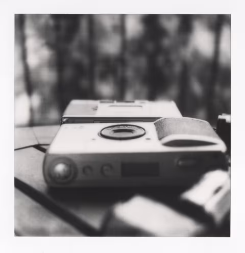 Up close: Ricoh GR1s. Further back: Minolta TC-1. The cameras are touching their bottom plates. As you can see, the GR1s is thinner than the TC-1, except for the hand grip area, where the film and the battery go.
