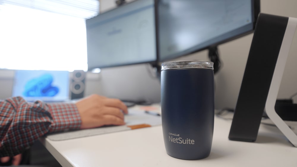 oracle netsuite thermus in the foreground of a blurred image of an anchor group employee at work
