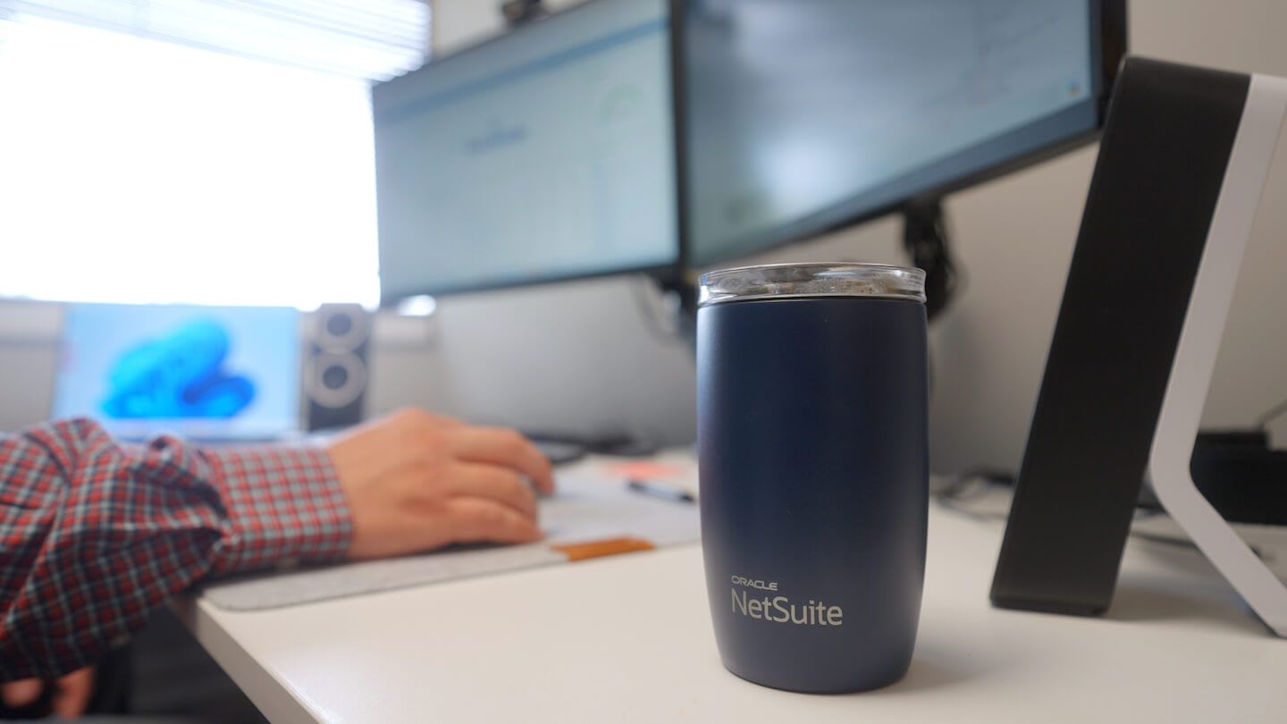 Oracle NetSuite mug at Anchor Group desk.