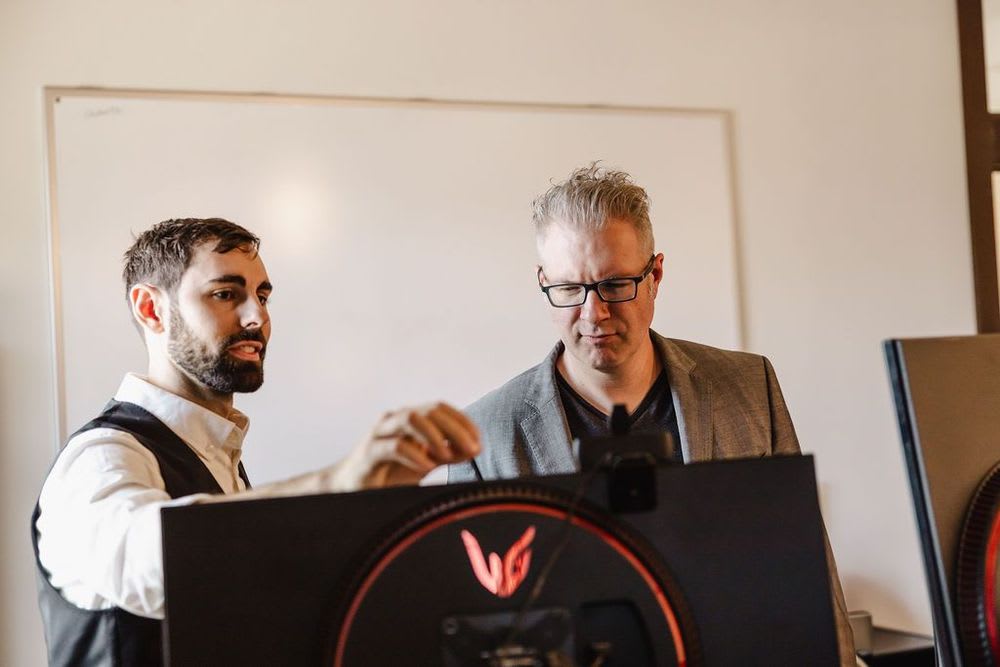 Two men focused on a computer screen, discussing the content displayed.