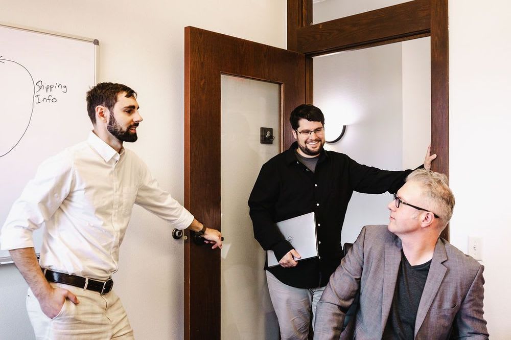 NetSuite consultant talking to two men in an office, sharing ideas and collaborating on a project.