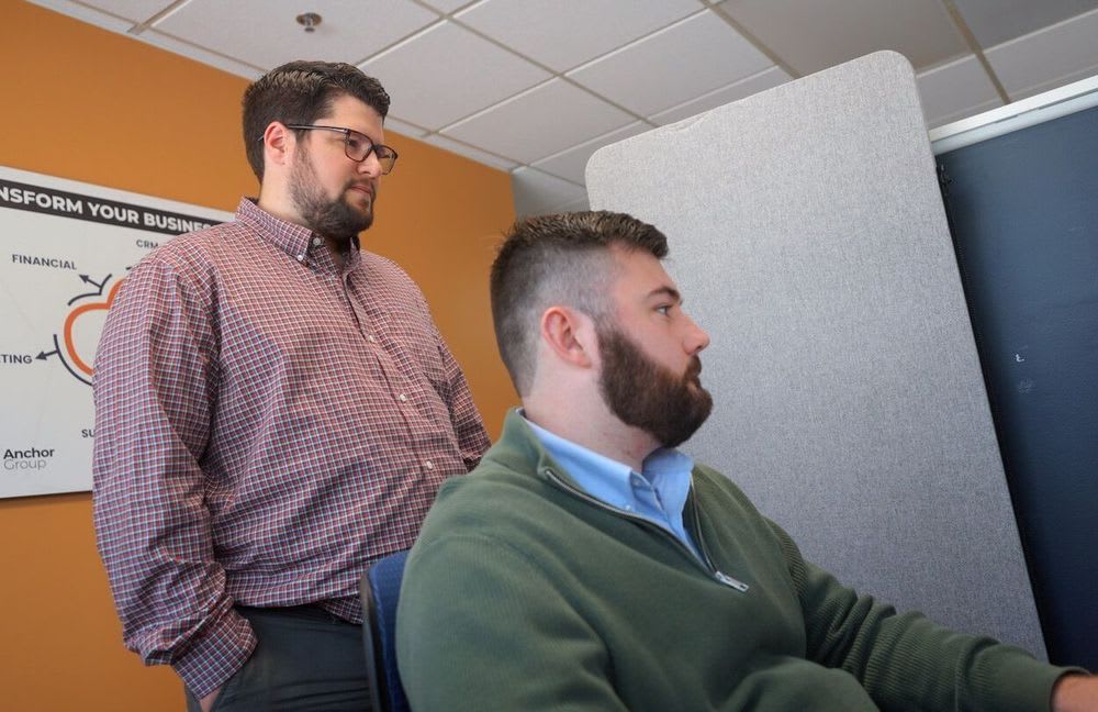 Anchor Group employees problem solving together in an office setting.