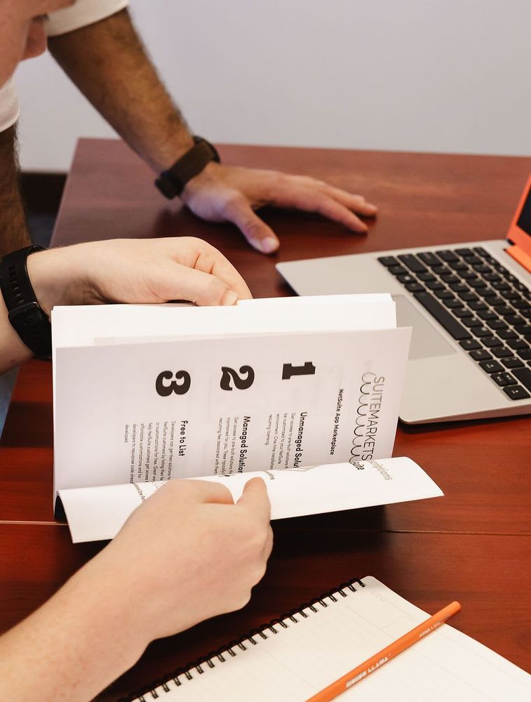 Two people are flipping through a book with numbering 1, 2, and 3 listed inside.