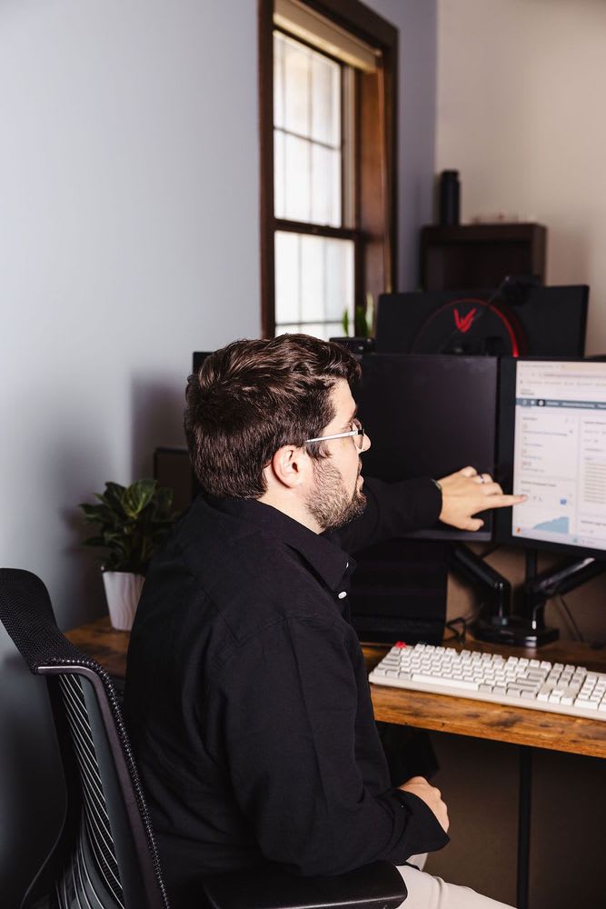 A person focused on a laptop computer, motioning to a specific point on the screen.
