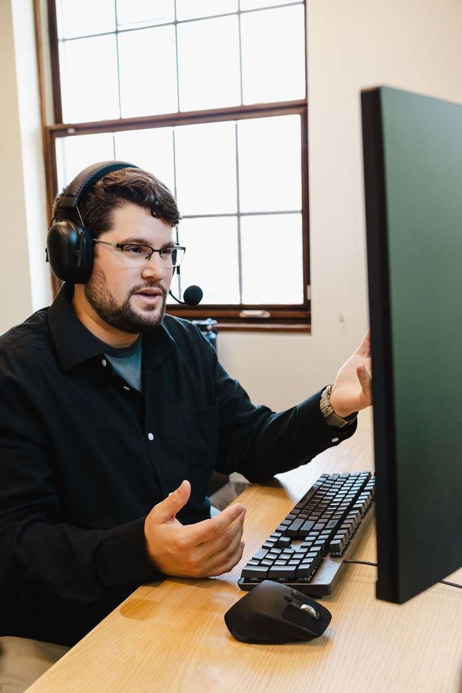 A man presenting emphatically with a laptop before him.