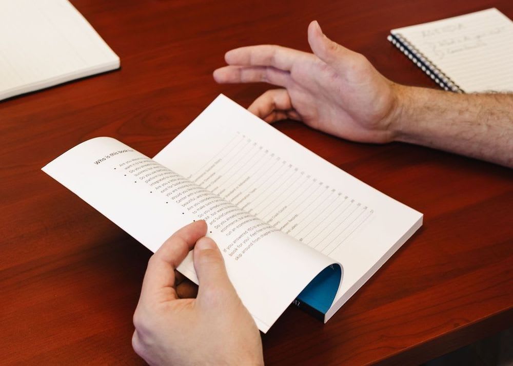 A person flipping through a small blue netsuite ecommerce book.