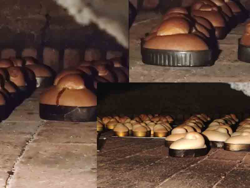 Charolas de pan horneándose dentro del horno tradicional de ladrillo