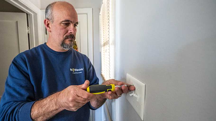 Electrician attaching a light switch to the wall.