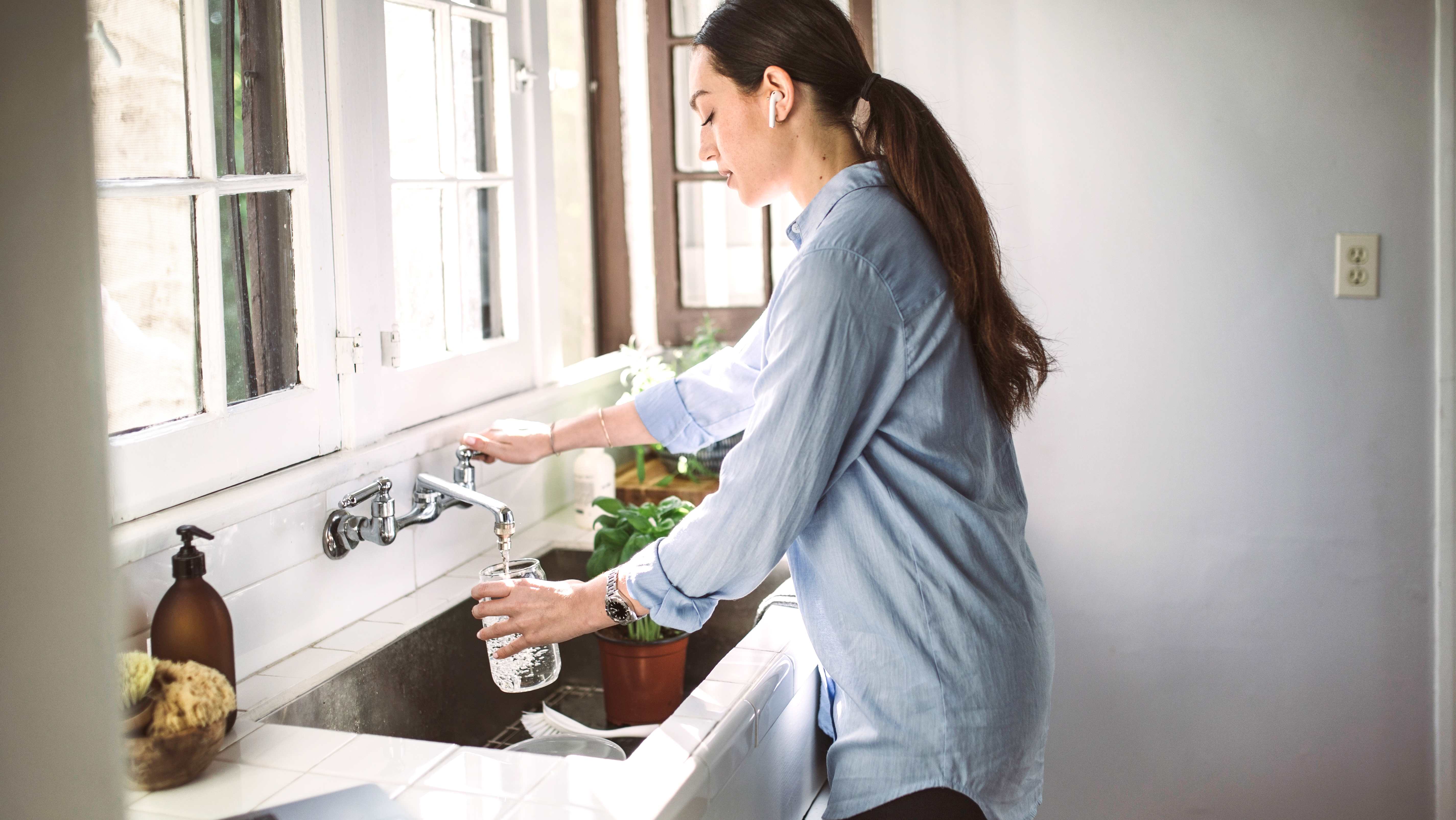 Woman in the kitchen filling up a jar with water