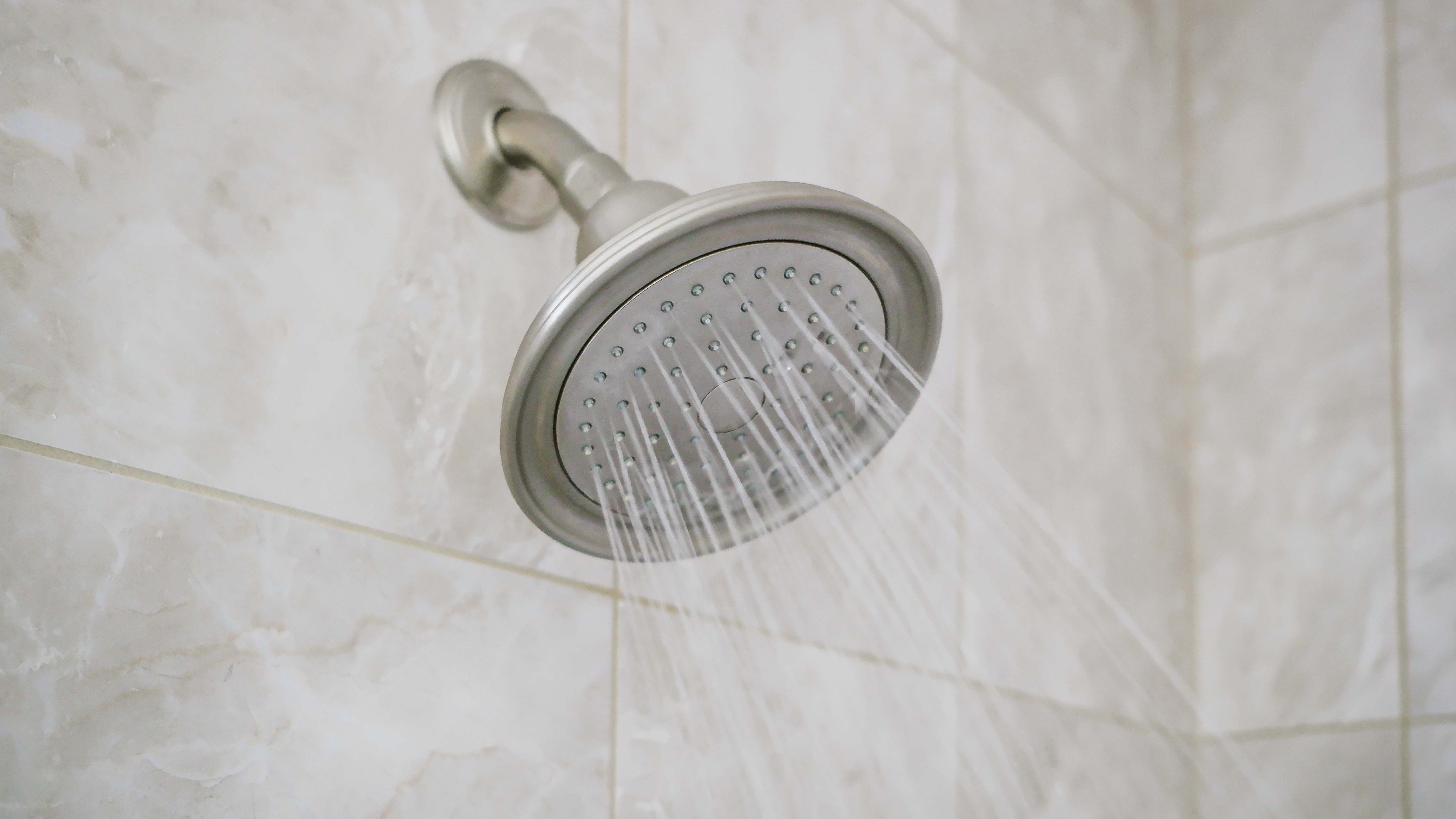 Shower head mounted to the wall with gray tiles