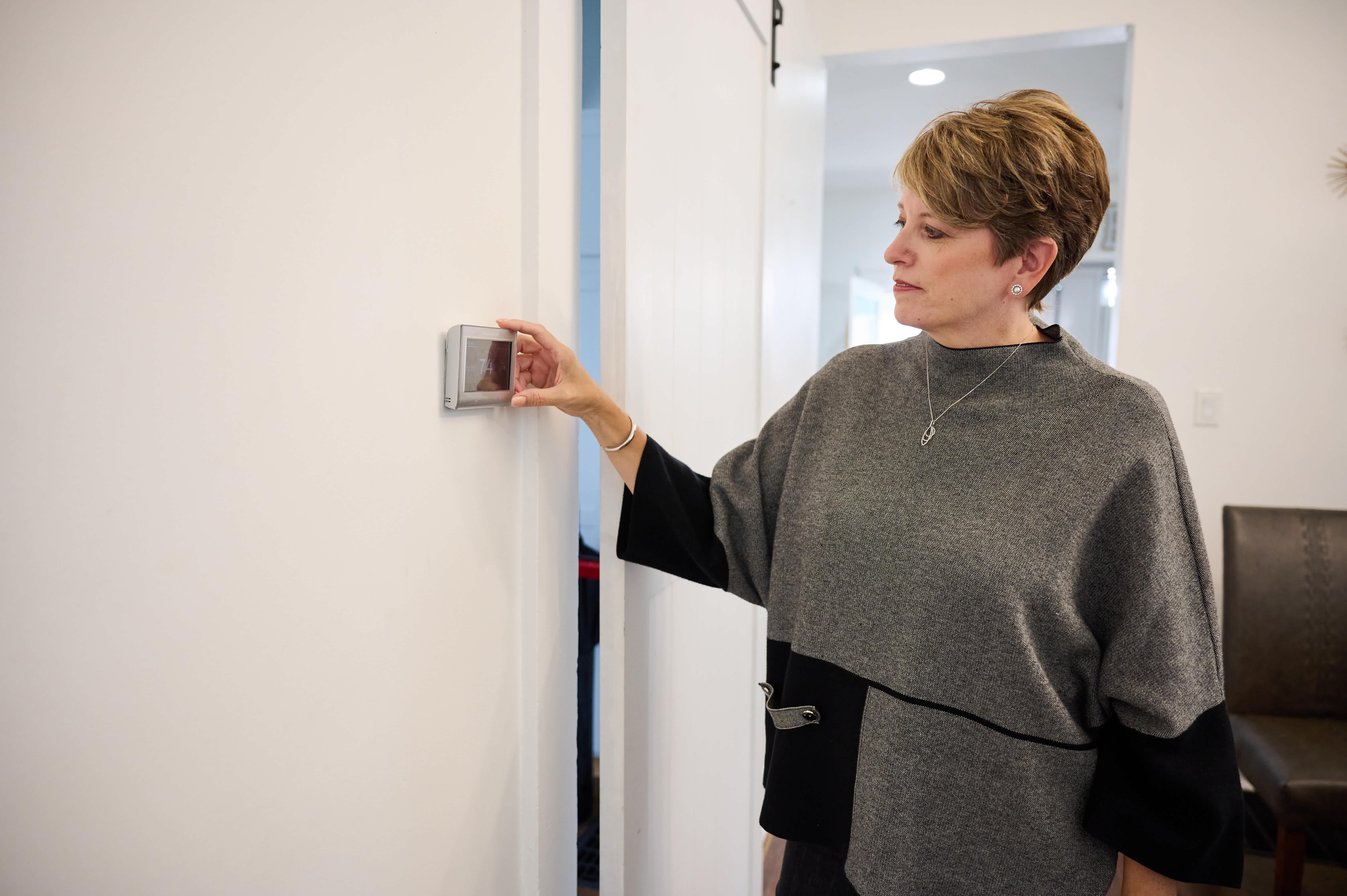 Angie Hicks looking at the smart thermostat installed in this home