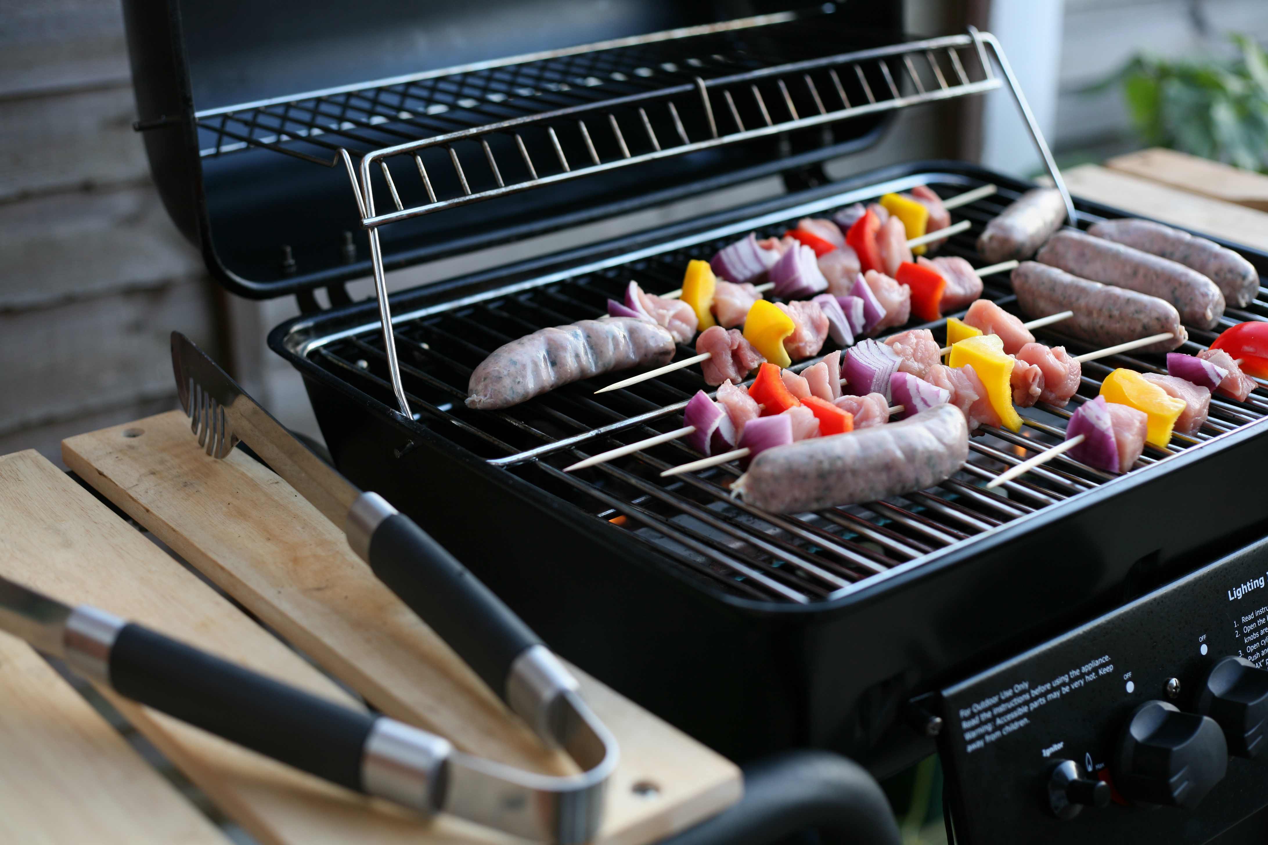 A gas grill sits on a patio with tools nearby, indicating it's undergoing repair to restore functionality for outdoor cooking.