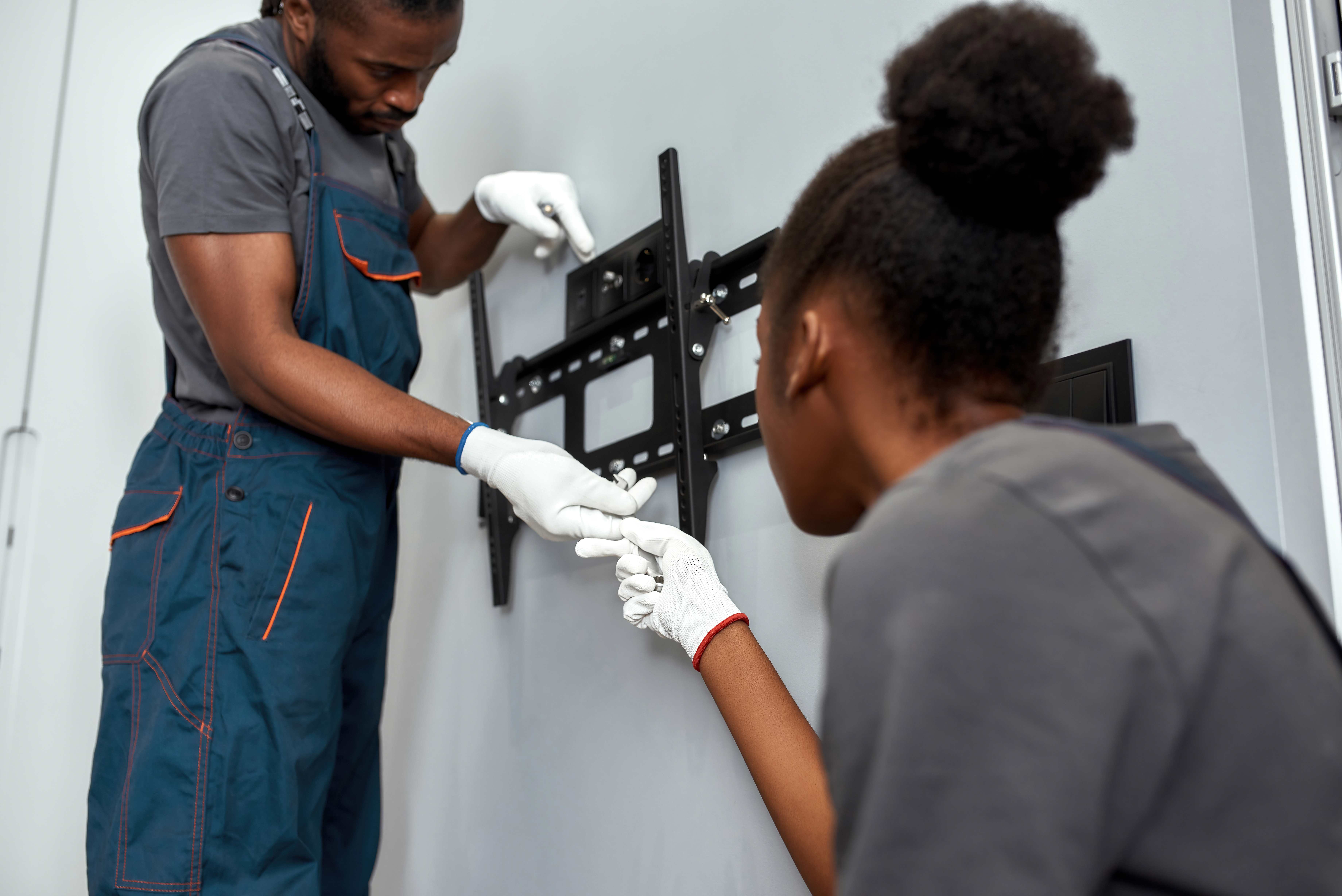 Team installing a flat-screen TV wall mount, securing it for optimal viewing and stability in a modern living room setup