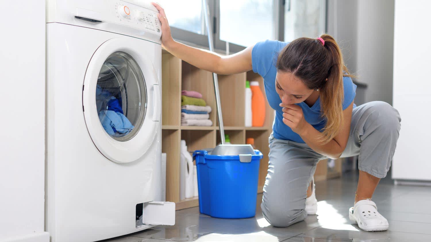 A woman checking the drain of a front-load washing machine