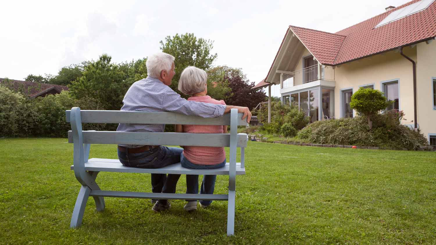 elderly couple sitting outside their home