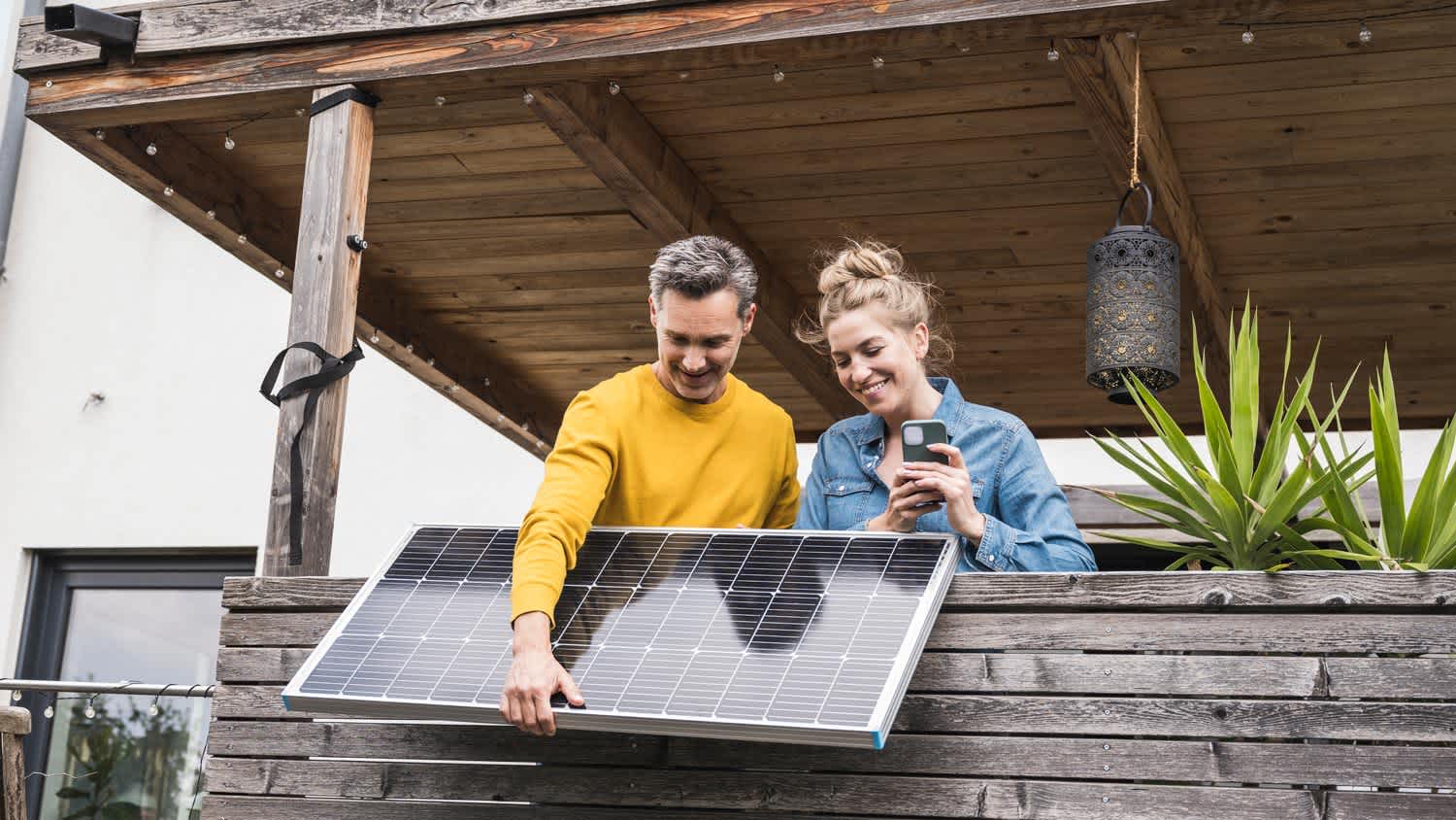Couple installing solar panel on wooden balcony