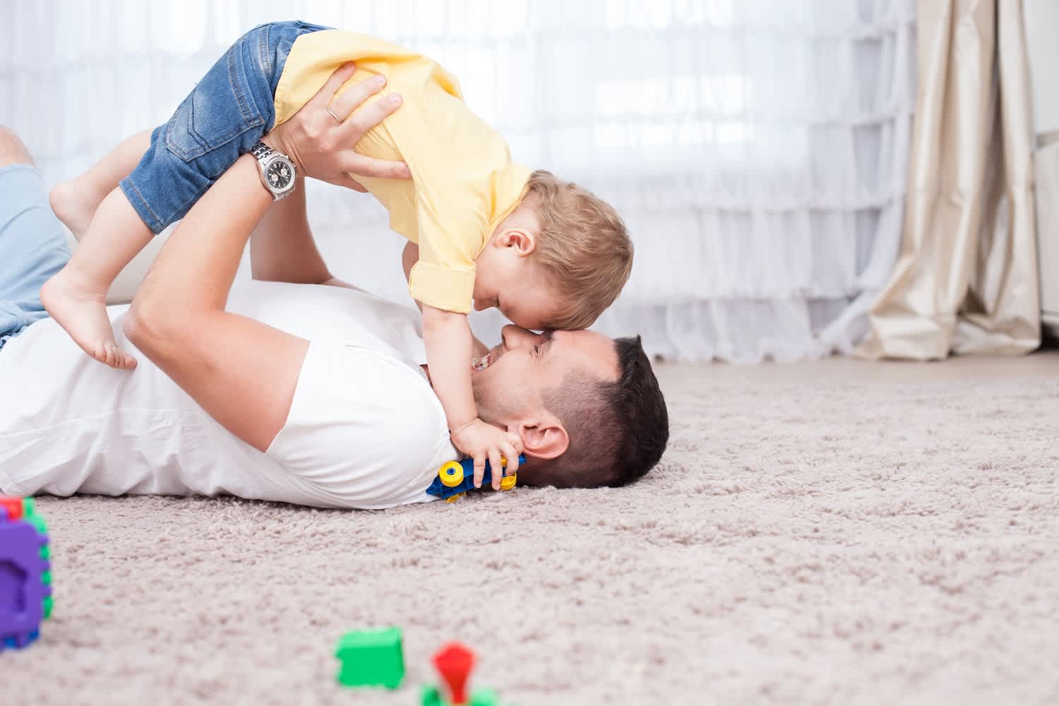 Father and son play in living room on carpet