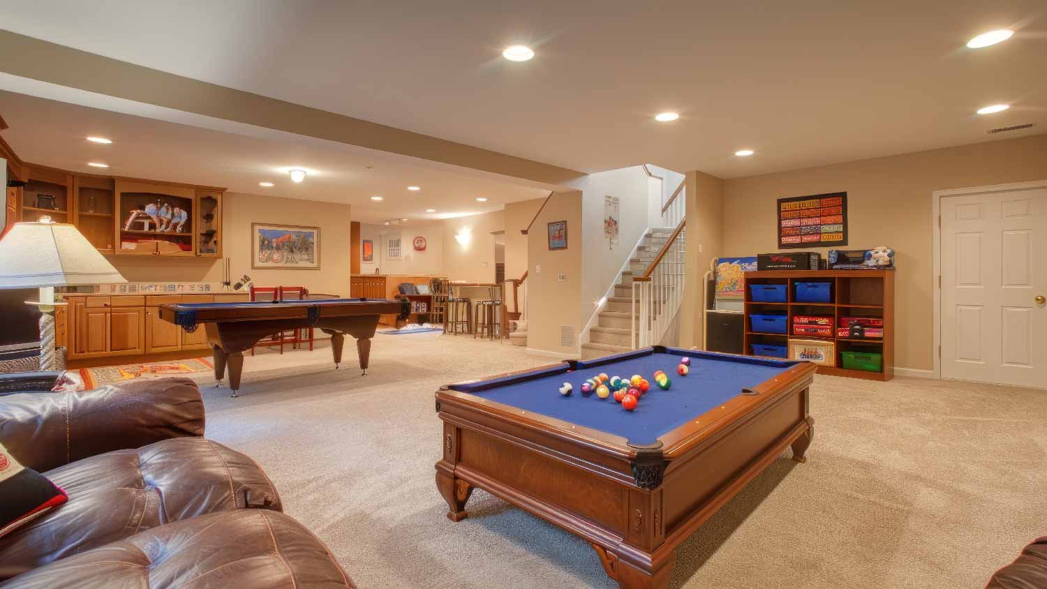 A carpeted basement with pool tables