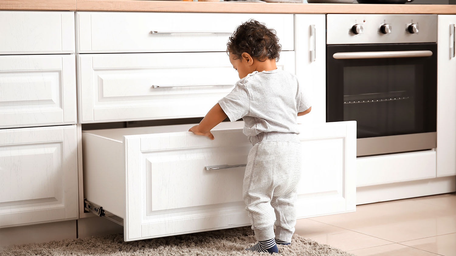 A child opens a kitchen drawer