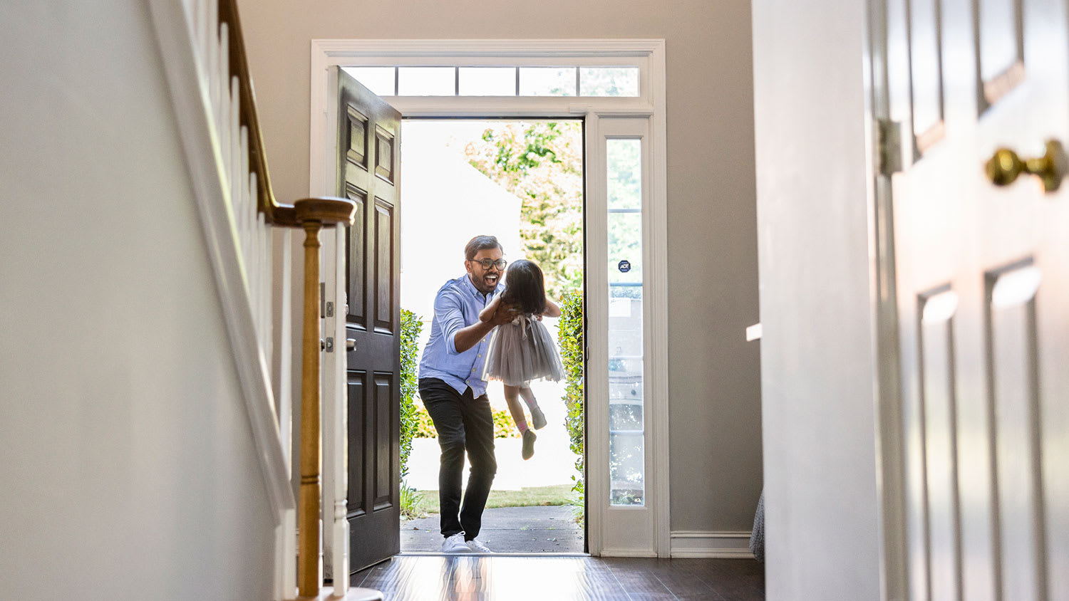 Father greeting and holding daughter in the entryway