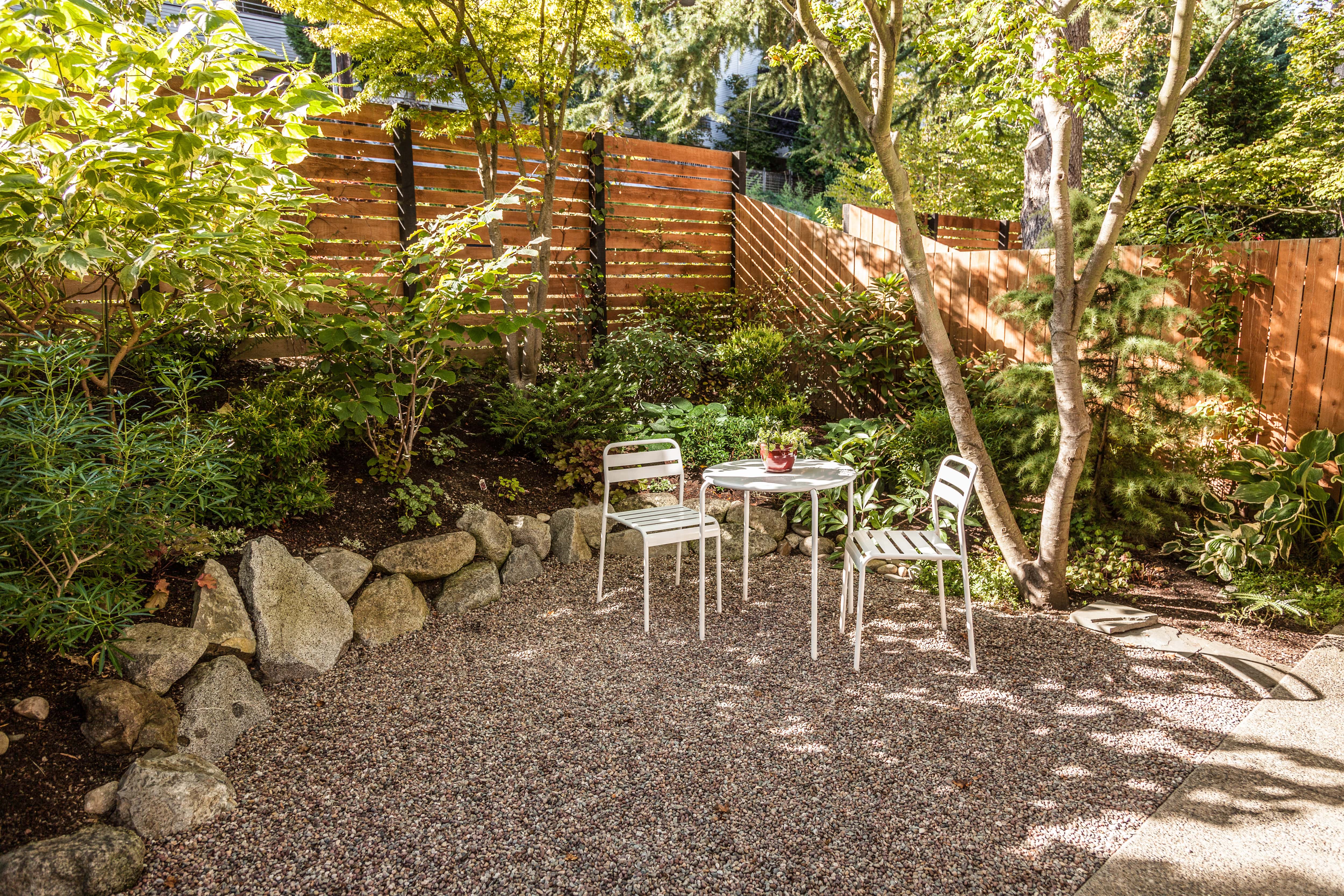 A backyard with a stained wood fence, table, and chairs