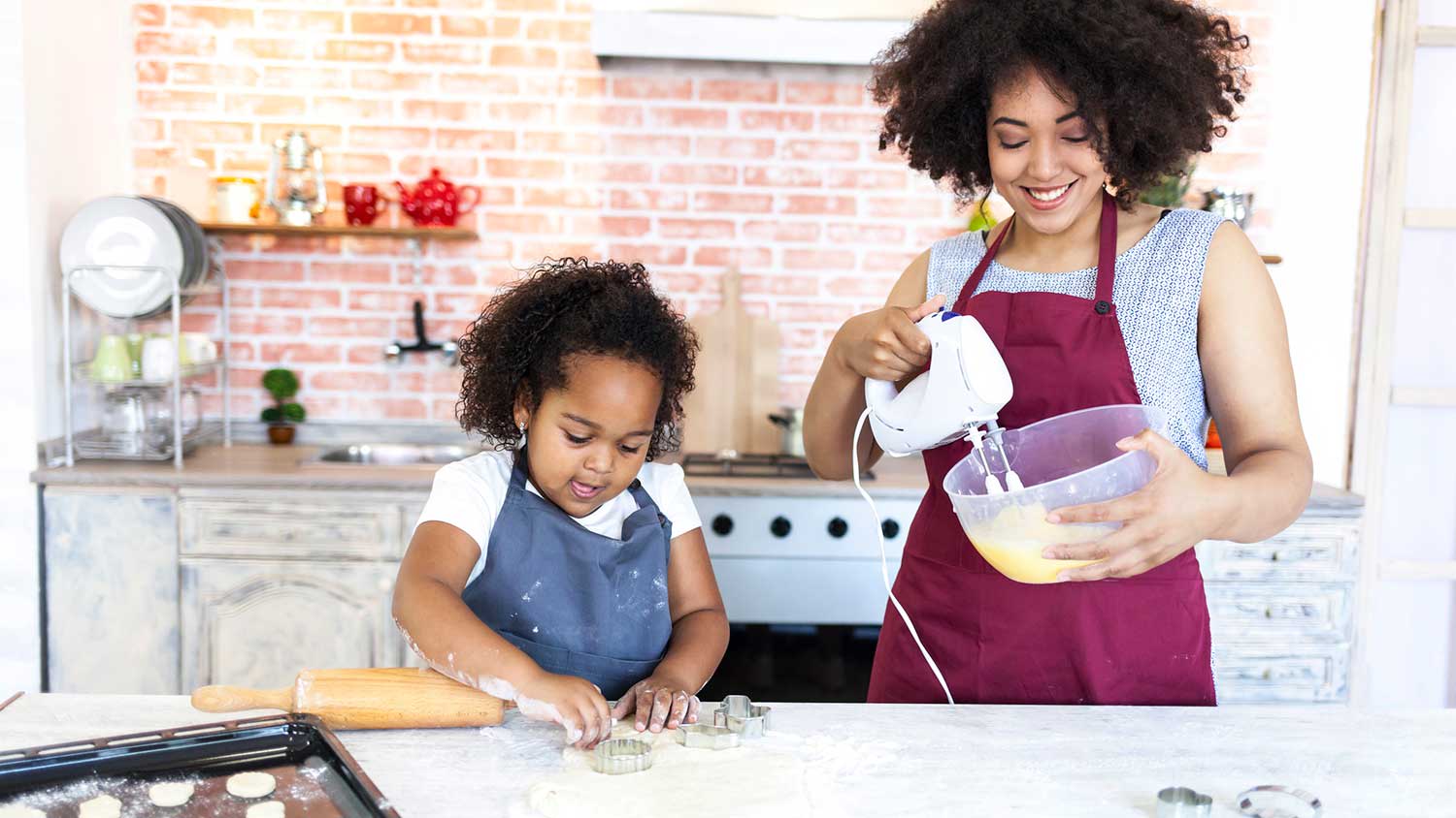 Mother and daughter in the kitchen mixing dough to make cookies