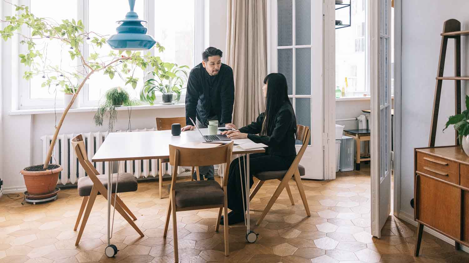 Couple in the dining room talking and using a laptop