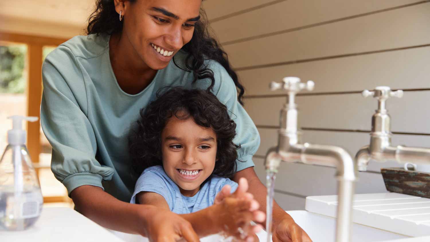 Mother helping son wash hands in sink