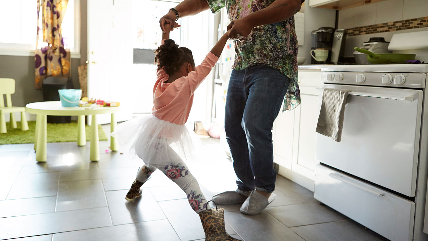 A father and daughter play in a kitchen
