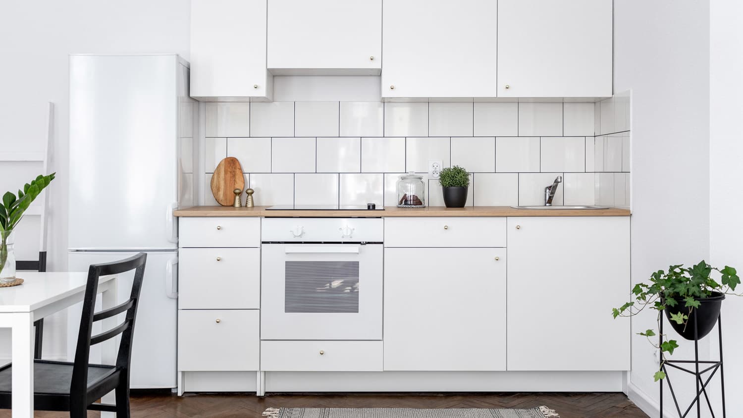 A kitchen with white cabinets and subway tiles