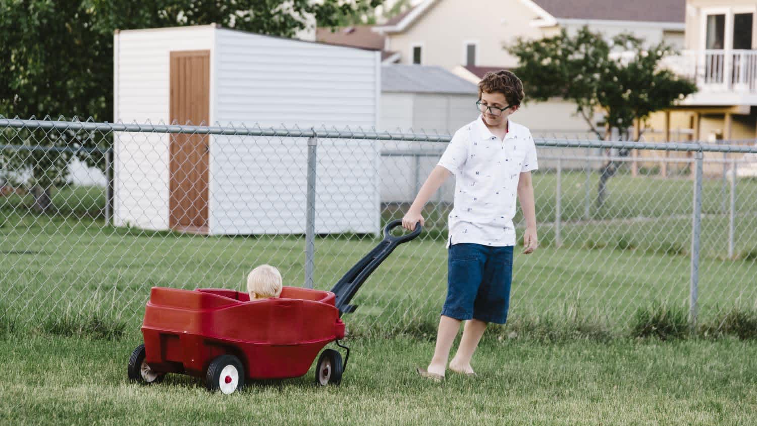 Boy pulling his nephew in a wagon in the family backyard
