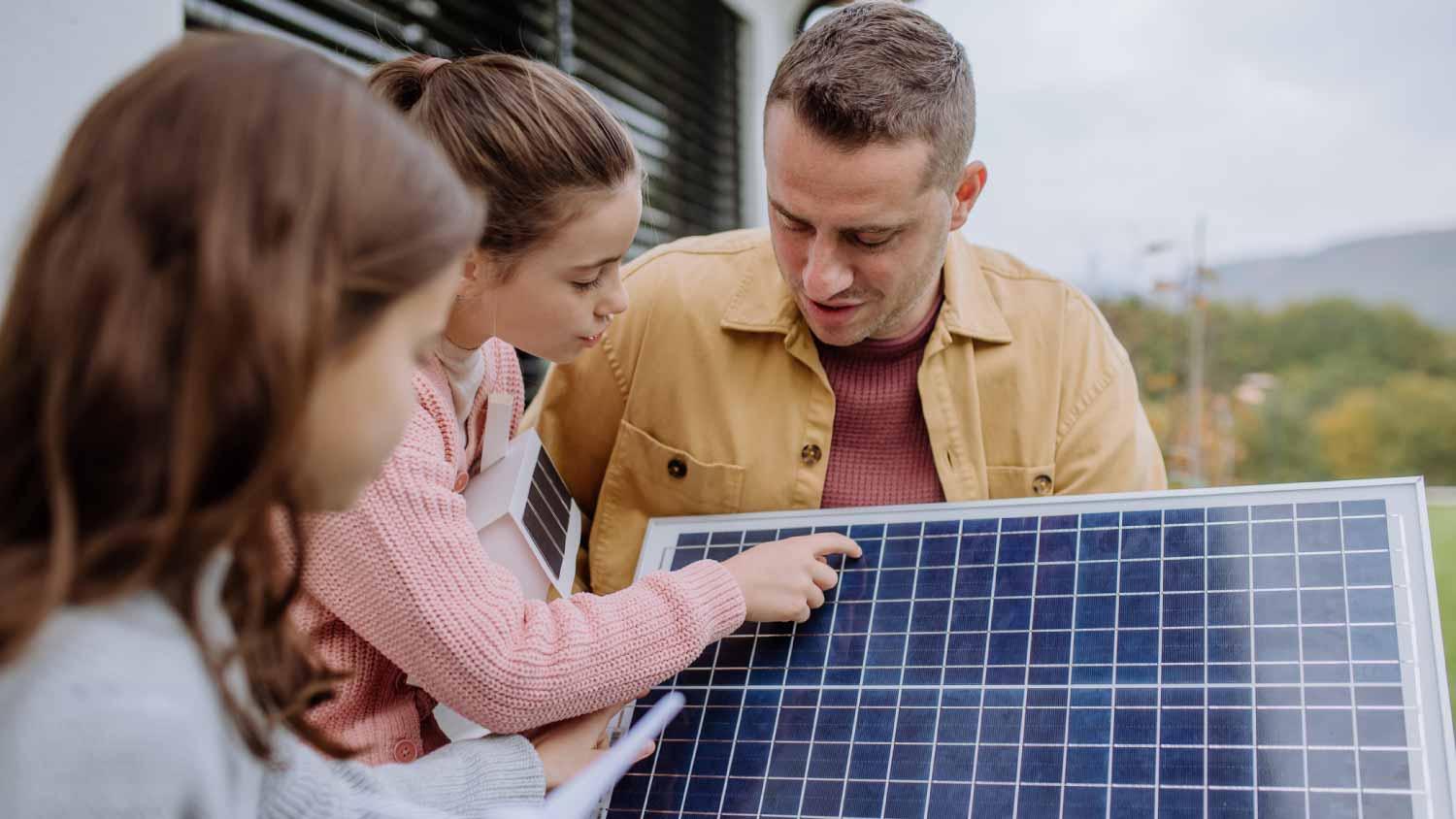 Girl holding model of house with solar panels