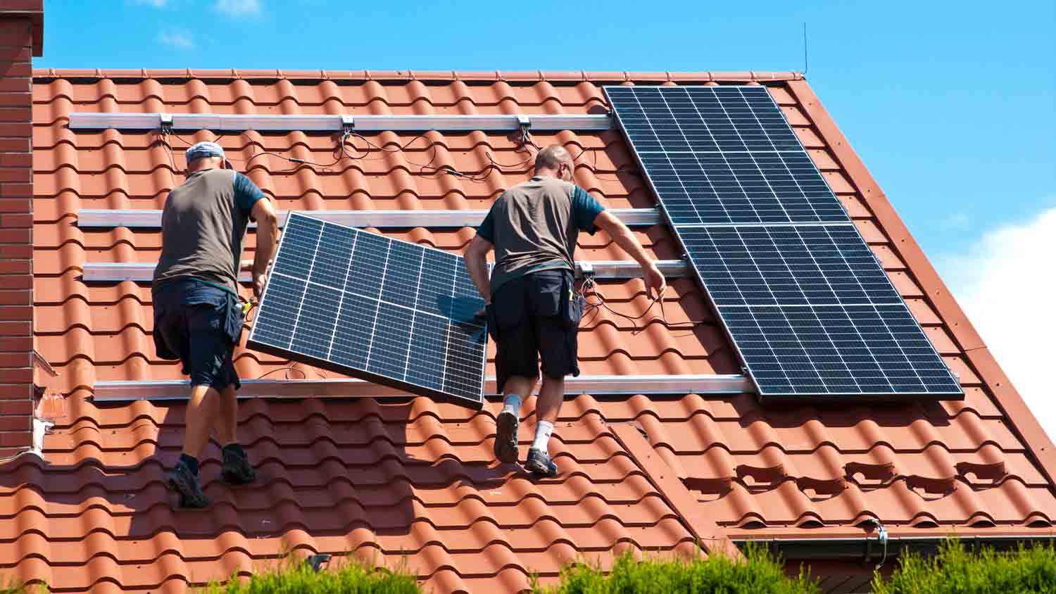 workers installing solar panels on roof