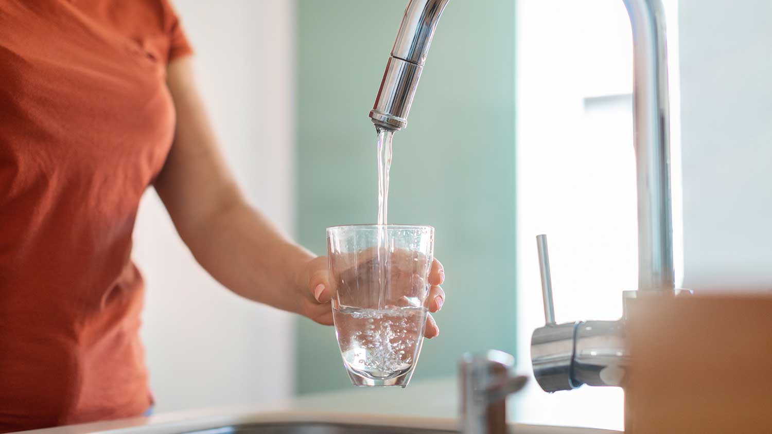 Woman filling glass with tap water