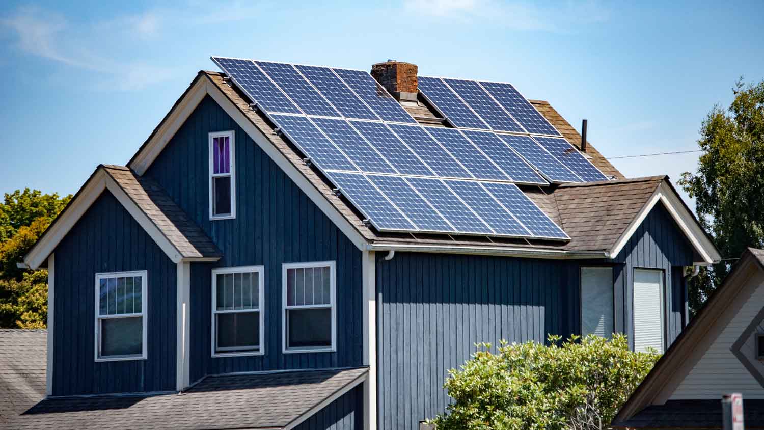 a blue house with roof covered in solar panels