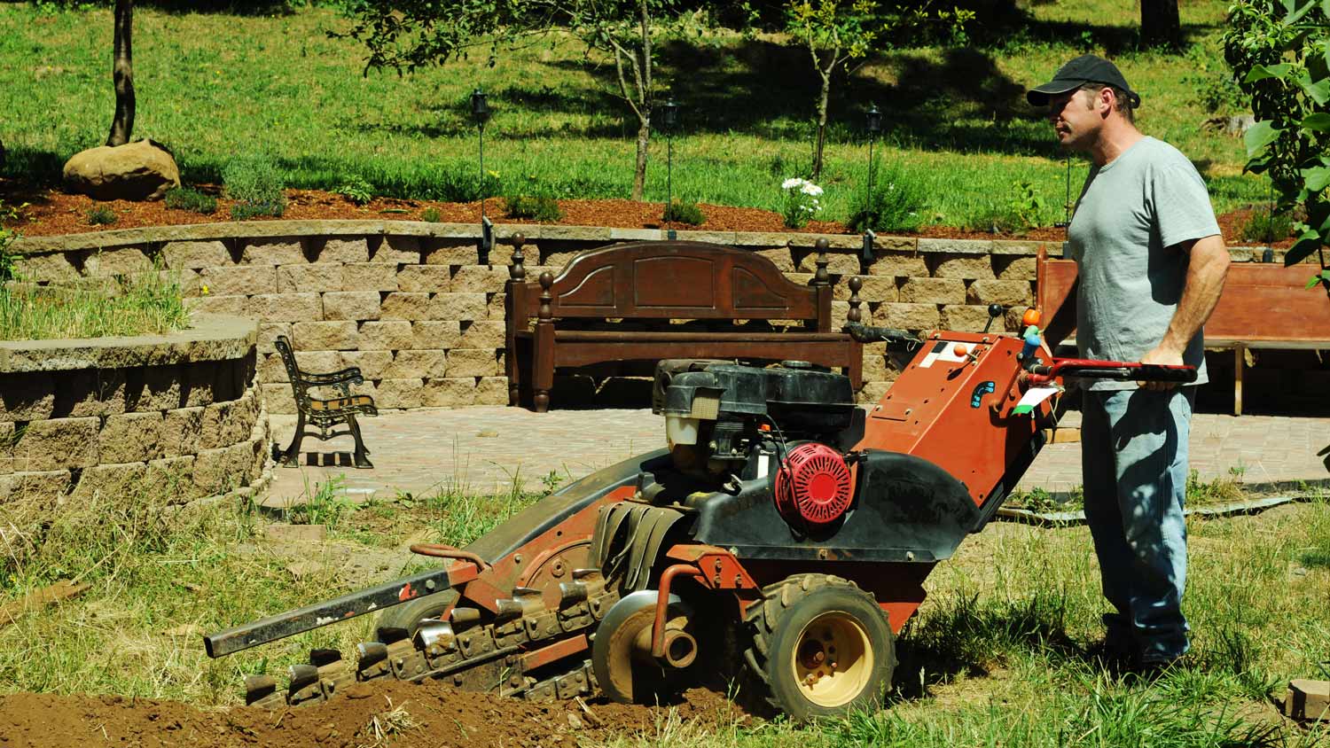 Man in yard with trench digging machine