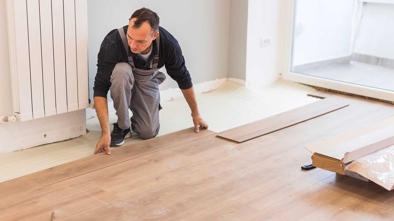 Contractor installing new vinyl flooring in the room