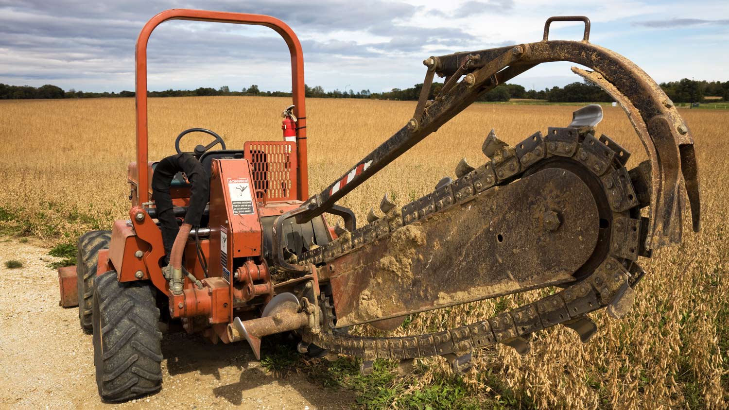 Orange trenching machine in field